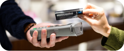 Hand holding a card reader as another hand taps a credit card on top.