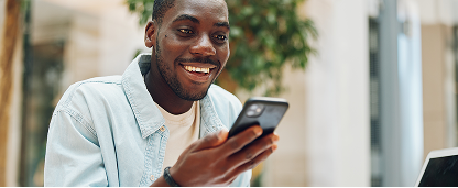 Man in a blue shirt looking at his smartphone screen.